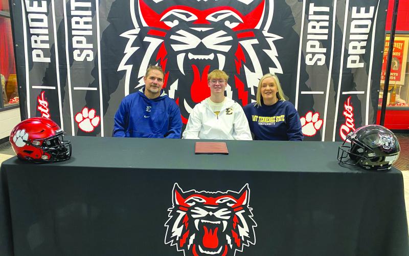 Submitted. RCHS senior football player Hayden Ross (middle) signs to play collegiately at East Tennessee State University with his parents by his side on Feb. 7. Ross will be a specialist/long-snapper for the Buccaneers.