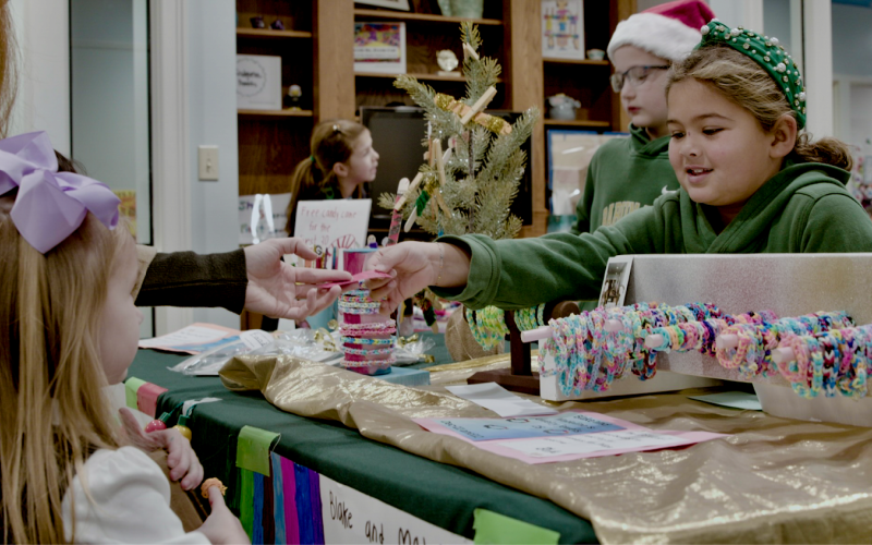 Submitted photo. Rabun Gap-Nacoochee School hosted its third annual Second Grade Marketplace on Tuesday, Dec. 12, where students learned entrepreneurship and economics while raising money for a community garden. Pictured, Blake Ruiz, Class of 2034 of Otto, N.C., interacts with a customer on market day.