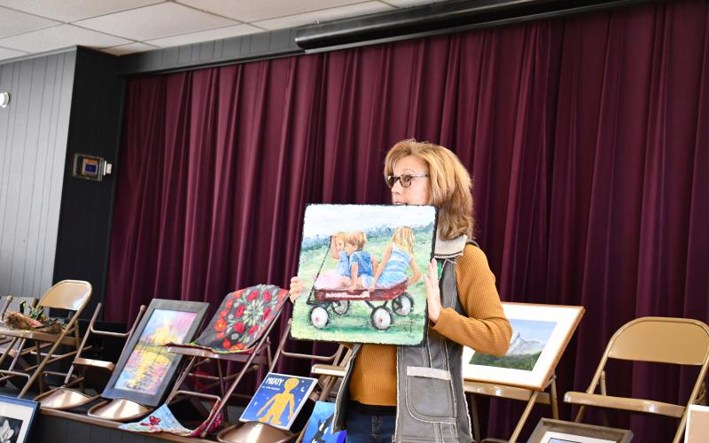 Megan Horn/The Clayton Tribune. This painting of three children in a red wagon playing outside by Guild member Cathy Jowers is inspired from the 1993 movie “Cool Runnings.”