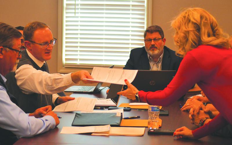 Enoch Autry/The Clayton Tribune. City of Clayton Attorney Mitch Baker hands RCWSA Finance Manager Traci Adams checks to help complete the sale of the water and sewer system on Monday at the new Clayton office.