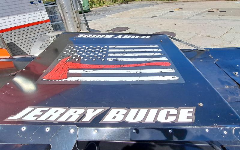 Conner Horn/The Clayton Tribune. This American Flag with Jerry Buice’s name and a firefighter symbol is displayed on the top of Buice’s “Big Unit 50” race car.