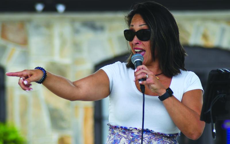 Enoch Autry/The Clayton Tribune. Monica Spears sings at the May 4 Dinglerfest in Dillard. Left: John Harrison has to do double take at the bagpipe-playing dinosaur artist Daniel Bollinger.