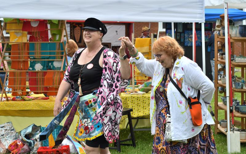 Enoch Autry/The Clayton Tribune. Tracy Allison and Sharon Bishop dance to the music at Dinglerfest in Dillard on May 4. Left: John Harrison has to do double take at the bagpipe-playing dinosaur artist Daniel Bollinger.