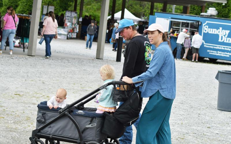 Enoch Autry/The Clayton Tribune. Ginny Thomas of Clayton pushes a cart carrying her daughters Patterson, 2-and-a-half, and Goldie, 7 months, at the Of These Mountains event as the girls’ grandfather from South Florida Tom Murphy enjoys the walk with them.