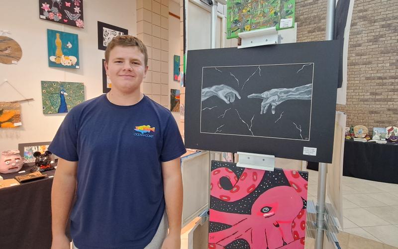 Megan Horn/The Clayton Tribune. Ninth Grade RCHS student David H. Griggs displays his mixed media “Creation of Adam” artwork during the RCHS and RCMS Art Showcase at the Fine Arts Building May 16. Left: RCHS senior Ryleigh Brotherton displays artwork in red clay titled “Friendly Miner."
