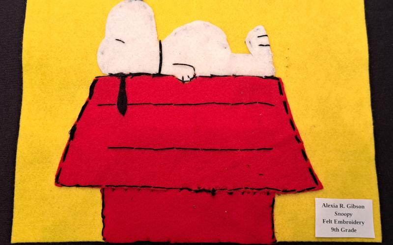 Megan Horn/The Clayton Tribune. RCHS Ninth grader Alexia R. Gibson displays this felt embroidery “Snoopy” art during the RCMS and RCHS Art Showcase in the Rabun County Schools Fine Arts Building May 16. Left: RCHS senior Ryleigh Brotherton displays artwork in red clay titled “Friendly Miner."