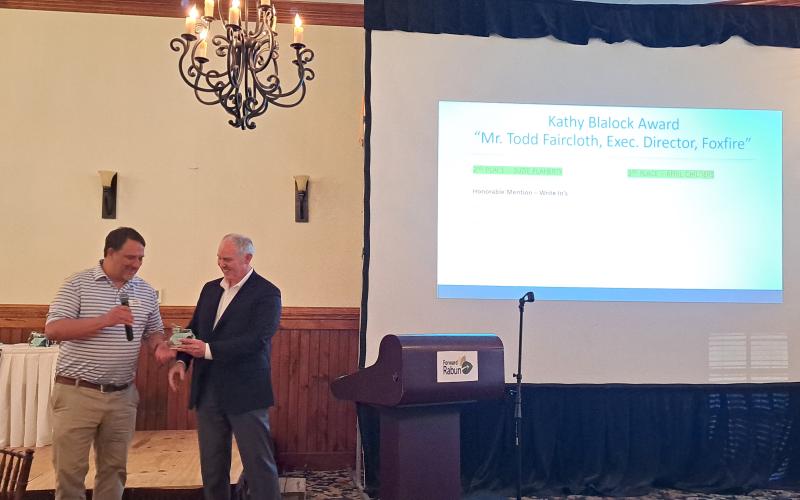 Megan Horn/The Clayton Tribune. Todd Faircloth, executive director of Foxfire, accepts the Kathy Blalock award from Rick Story, Forward Rabun/Rabun County Chamber of Commerce president and director of development for Rabun County, during the May 16 Forward Rabun Business Awards Breakfast. Faircloth thanked the community for the support in his remarks.