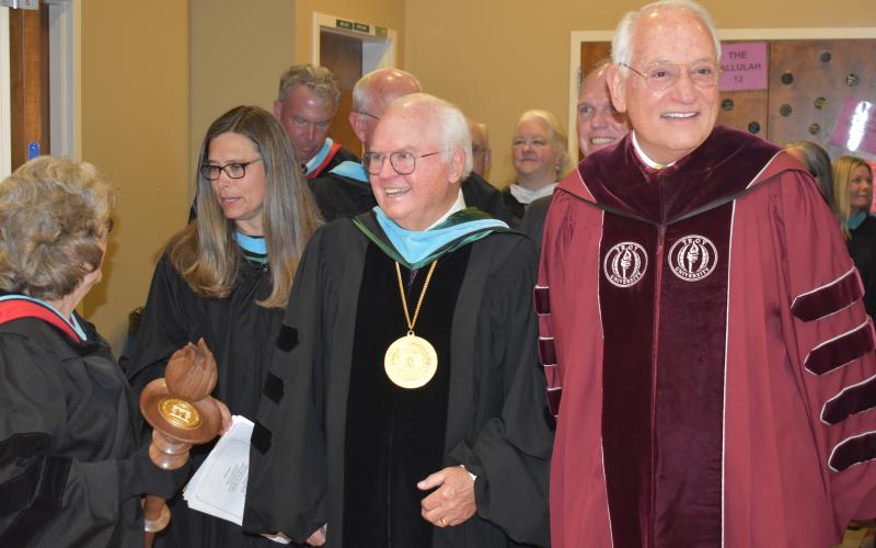 Matthew Osborne/CNI News Service. TFS Head of School Larry Peevy walks into the Student Athletic Center with his college roommate Dr. Jack Hawkins Jr., the chancellor of Troy University, and the graduation ceremony keynote speaker.