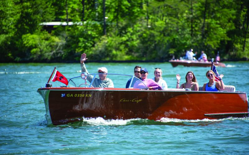 Submitted photos. Wooden boat during the parade on Lake Burton. Boat owner waves to the crowd.