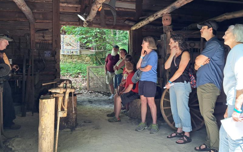 Megan Horn/The Clayton Tribune. Attendees at Foxfire Heritage Days last weekend watch as Wind Chapman (left) demonstrates blacksmithing. The fundraiser festival was held June 7 and 8 during the 50th anniversary of the museum.