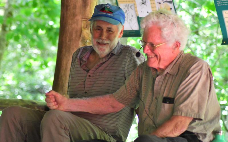 Enoch Autry/The Clayton Tribune. John Lane and Doug Woodward share a laugh at the picnic area at Warwoman Dell. Lane, an author, and Woodward, a former stuntman, told people at the event about the early days of the designation for the river. Left: Volunteer Jim Chance chops trees in the Warwoman Dell area as part of the early morning cleanup. Others walked trails picking up trash.