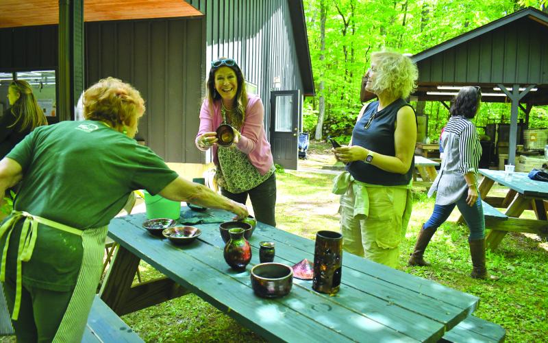 Enoch Autry/The Clayton Tribune. Kristin Mueller of Atlanta proudly shows her pottery to her sister Karin Mueller (right) at the Hambidge Center open house event on May 11. The U-Do-Raku activity was popular as pots were glazed and fired. Left: Christie Lyons and 13-year-old daughter Tricia Lyons of Lawrenceville work on their pottery at the open house. Tricia attends Hudgens Art School in Duluth.