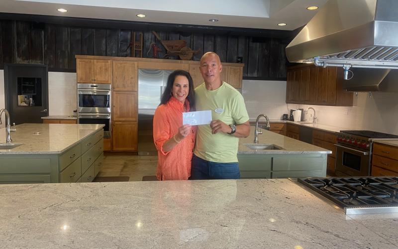 Submitted photo. Abby Jackson hands a donation check of $1,500 to James Brim, director of the Food Bank of Northeast Georgia Mountain Branch, for summer creative cooking classes for children. The Teaching Kitchen is presenting “Creative Cooking: Learning to Use What’s In Your Kitchen!” in June and July.