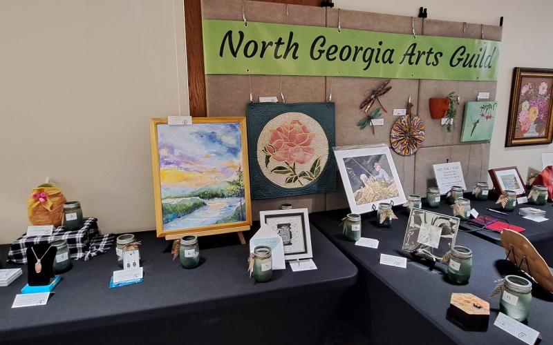 Proceeds from the bake sale and “Art for a Buck” at the Painted Fern Art Festival went to the North Georgia Arts Guild Scholarship program. The fund received over $3,000 from the “Art for a Buck” drawing, bake sale and T-shirt sales. Below: Submitted. At the 2024 Painted Fern Art Festival, Sean and Ebony Wilson (left) were the Producers’ Choice Award winners for Best Booth with their woodworking. Sharon Mumbi (right) was chosen by show visitors and awarded the Peoples’ Choice for Best in Show.