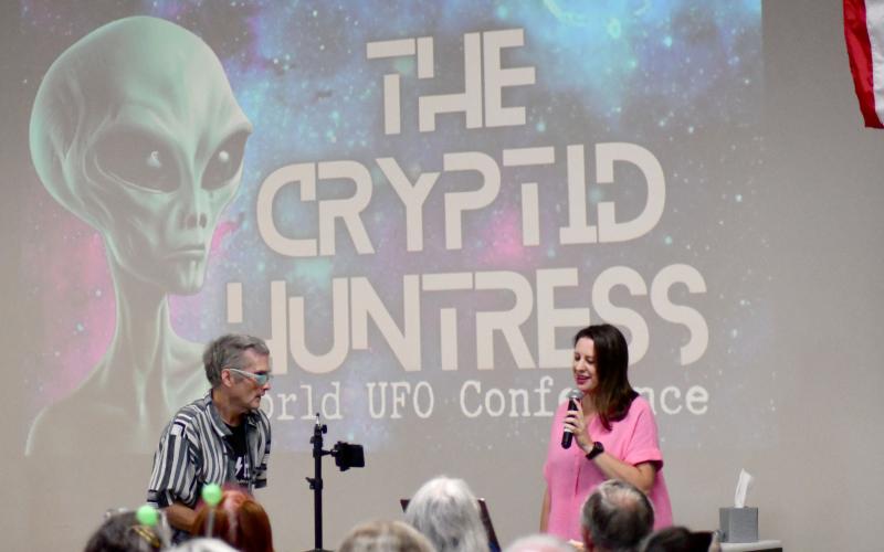 Enoch Autry/The Clayton Tribune. With Les Durrant standing up front with her, Jessica Jones, “The Cryptid Huntress,” addresses the audience in the Food Bank of Northeast Georgia on June 29. Below: Those in attendance even donned springy antenna to salute the visitors from afar.