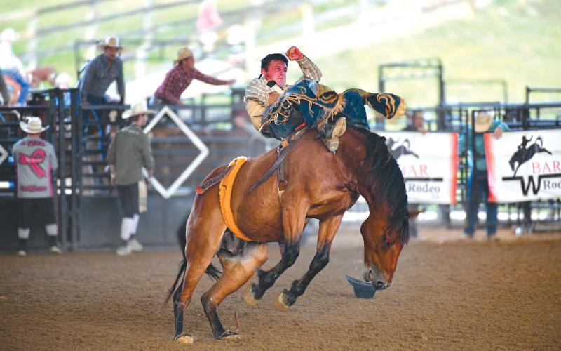 Wade Cheek/The Clayton Tribune.  Bareback rider Tanner Phipps holds tight amid a rowdy bucking horse at this past weekend’s Bar W Rodeo from July 5 to July 6 at the Rabun Arena. Phipps came in first in the bareback riding event.