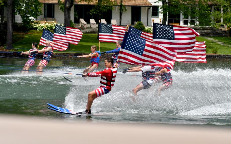 Enoch Autry/The Clayton Tribune. With their American flags unfurled, the Ski Patriots pass homes on Lake Burton on July 7.