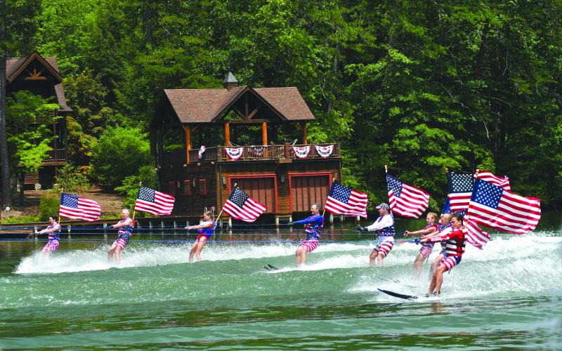 Enoch Autry/The Clayton Tribune. With their American flags unfurled, the Ski Patriots pass homes on Lake Burton on July 7.