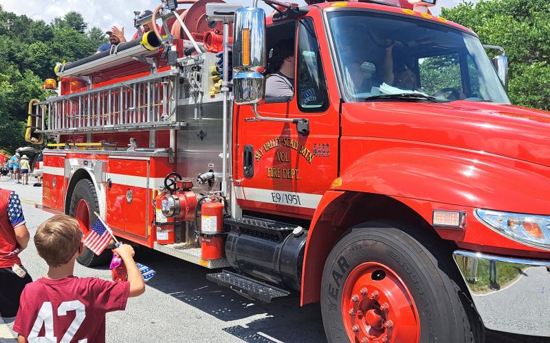 Megan Horn/The Clayton Tribune. Sky Valley-Scaly Mountain Volunteer Fire &amp; Rescue in the Sky Valley Indepenence Day Grand Parade. Below: Megan Horn/The Clayton Tribune. Tom DesOrmeaux and Caroline Cobb, 2, don patriotic apparel and wave a flag while awaiting the start of the Sky Valley Independence Day rubber duck race.