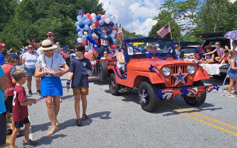 Megan Horn/The Clayton Tribune. Hundreds of people lined up to view the patriotic Sky Valley Grand Parade. Below: Megan Horn/The Clayton Tribune. Tom DesOrmeaux and Caroline Cobb, 2, don patriotic apparel and wave a flag while awaiting the start of the Sky Valley Independence Day rubber duck race.