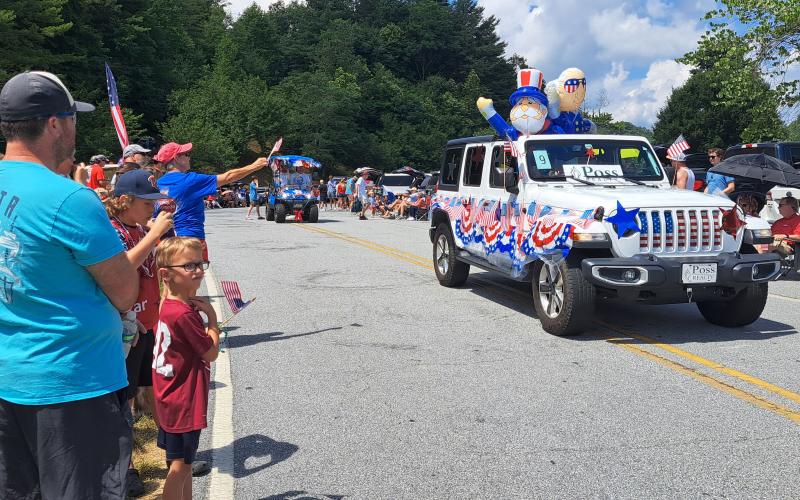 Megan Horn/The Clayton Tribune. Hundreds of people lined up to view the patriotic Sky Valley Grand Parade. Below: Megan Horn/The Clayton Tribune. Tom DesOrmeaux and Caroline Cobb, 2, don patriotic apparel and wave a flag while awaiting the start of the Sky Valley Independence Day rubber duck race.