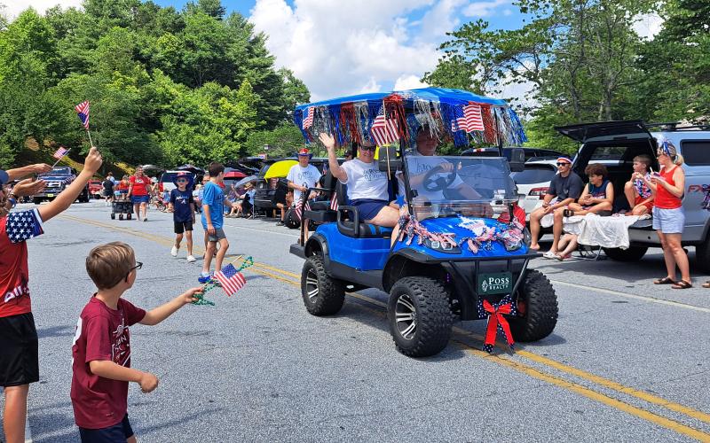 Megan Horn/The Clayton Tribune. Hundreds of people lined up to view the patriotic Sky Valley Grand Parade. Below: Megan Horn/The Clayton Tribune. Tom DesOrmeaux and Caroline Cobb, 2, don patriotic apparel and wave a flag while awaiting the start of the Sky Valley Independence Day rubber duck race.
