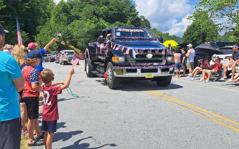 Megan Horn/The Clayton Tribune. Hundreds of people lined up to view the patriotic Sky Valley Grand Parade. Below: Megan Horn/The Clayton Tribune. Tom DesOrmeaux and Caroline Cobb, 2, don patriotic apparel and wave a flag while awaiting the start of the Sky Valley Independence Day rubber duck race.
