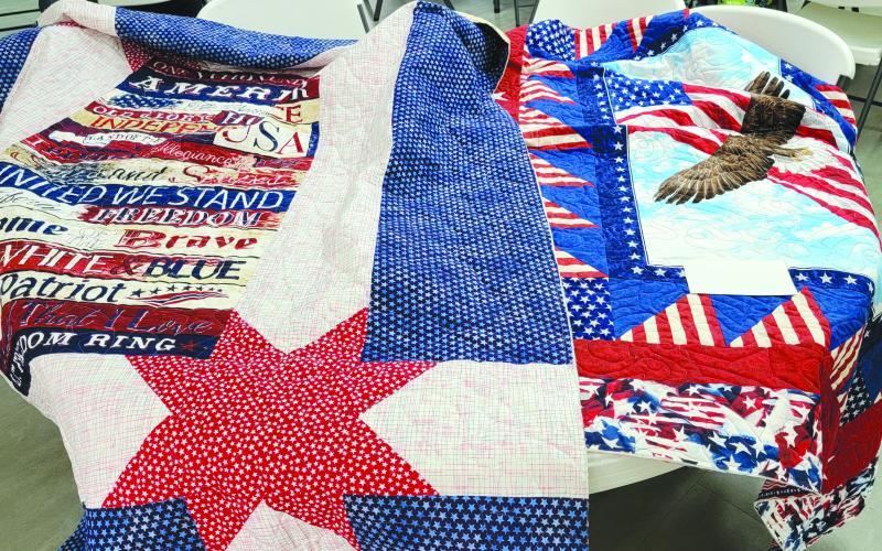 Submitted photo. Patriotic quilts created by the Northeast Georgia Chapter of Quilts of Valor will be presented to Active Duty and Veteran members of the military. Below: Jeanie Whitworth makes a red, white and blue quilt during the “Quilt-a-thon” April 18-20 with the Northeast Georgia Chapter of Quilts of Valor.