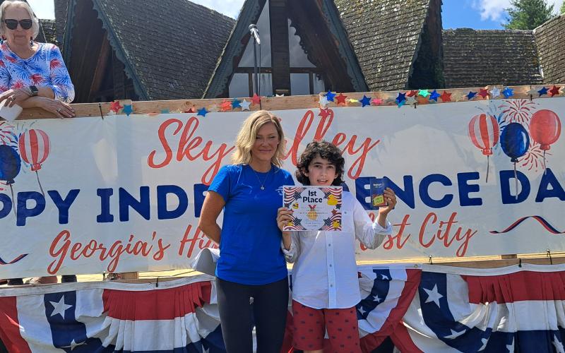 Megan Horn/The Clayton Tribune. Gabriel Garces, 12, won First Place in the rubber duck race with duck number 242. Below: Megan Horn/The Clayton Tribune. Tom DesOrmeaux and Caroline Cobb, 2, don patriotic apparel and wave a flag while awaiting the start of the Sky Valley Independence Day rubber duck race.