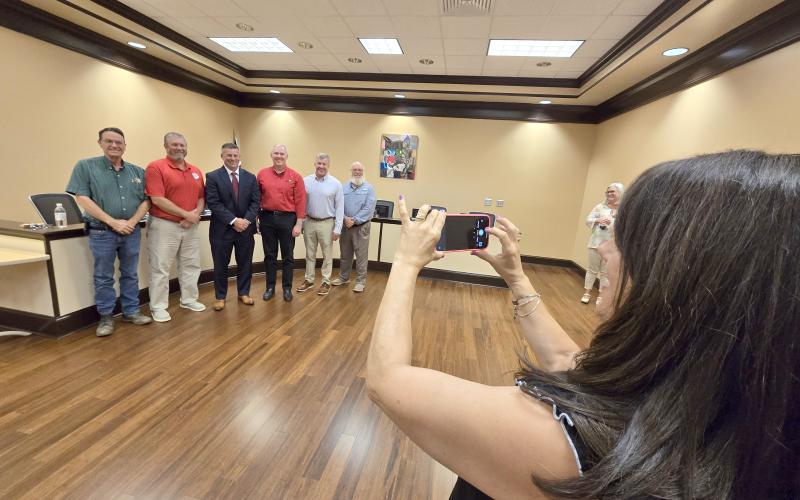 Enoch Autry/The Clayton Tribune. Anglea Cole takes a photograph of the Rabun County school board members and her husband Steven Cole (center) after Steven Cole was officially approved as the school system’s new superintendent. Standing on the far right is retiring superintendent Dr. April Childers.
