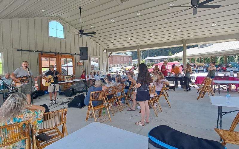 Megan Horn/The Clayton Tribune. A crowd of people enjoy music by the band Blue Ridge Lonesome during last Saturday’s  Rockin’ Mountain Motor Show. They also got the chance to buy T-shirts and participate in a 50/50 raffle.