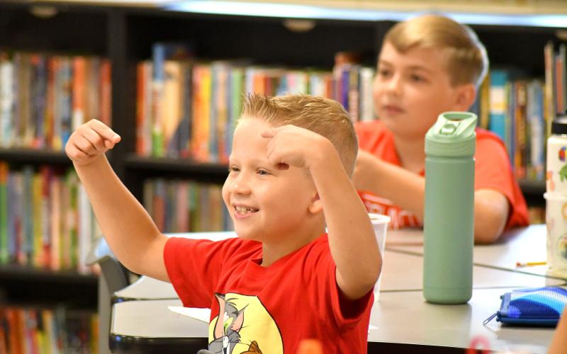 Enoch Autry/The Clayton Tribune.  Jason Hutcheson reacts to his fourth grade teacher Lee Bass’ question. Below: School Resource Deputy Sgt. Lindsey Owens directs school traffic on the first day Tuesday, Aug. 6.