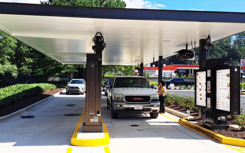 Megan Horn/The Clayton Tribune.  Team members help customers in the drive-thru lanes. Below: Those who order from the Chick-fil-A mobile app can go through the right “mobile-thru” lane at the restaurant and scan a QR code to obtain their order.