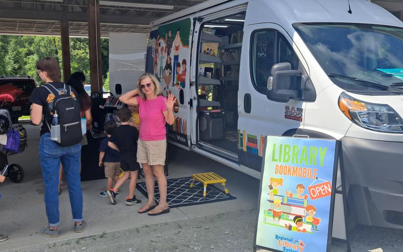 Megan Horn/The Clayton Tribune. The Northeast Georgia Regional Library System Library Bookmobile hosted many patrons during the Habitat for Humanity of Rabun County Touch-A-Truck event. Kim Gurtler waves in the foreground. Below: James Reddy, 4, and Jones Reddy, 2, enjoy their time climbing into the driver’s seat of this 1960 Fiat Multipla presented by Capital City Home Loans at the Habitat for Humanity Touch-A-Truck event.