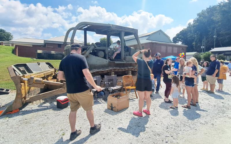 Megan Horn/The Clayton Tribune. Families interact with a Mack Tractor Trailer, Pitts Lowboy, D7 Dozer Caterpillar presented by Nichols Contracting, Inc. Below: James Reddy, 4, and Jones Reddy, 2, enjoy their time climbing into the driver’s seat of this 1960 Fiat Multipla presented by Capital City Home Loans at the Habitat for Humanity Touch-A-Truck event.
