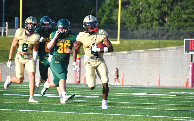 Wade Cheek/The Clayton Tribune. Rabun Gap junior CJ Willingham races past AC Reynolds for a TD at host Rabun County High School on Aug. 9. In the two quarters, RGNS outscored the Rockets 26-7.