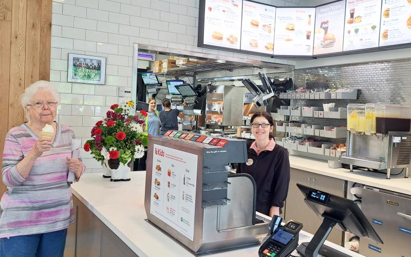 Megan Horn/The Clayton Tribune. Customer Linda Bradley with team member Kourtney. Below: Those who order from the Chick-fil-A mobile app can go through the right “mobile-thru” lane at the restaurant and scan a QR code to obtain their order.