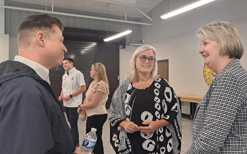 Megan Horn/The Clayton Tribune. Rabun County Schools Superintendent Dr. April Childers mingles with school officials, community leaders and board of education members during her retirement reception at the Rabun County Agricenter Tuesday. Pictured are Tony Penrose (left), Childers and Kathy McClure. Childers officially retires Sept. 30 and Steven Cole will become the full-time superintendent. Below: Rabun County Schools Superintendent Dr. April Childers converses with Mickey Duvall during her reception.