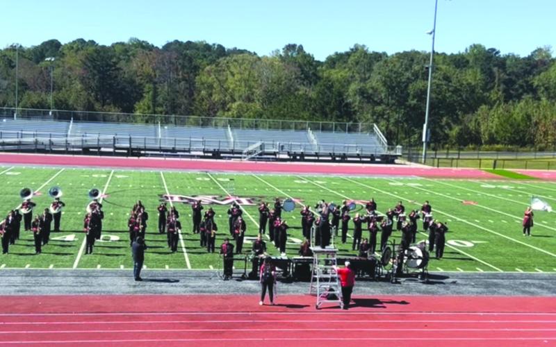 On the field at the Jaguar Classic competition is the Rabun County Wildcat Marching Band at New Manchester High School in Douglasville, Ga., before starting its set. Below: Following the Jaguar Classic, Lillian Seabolt, color guard captain; Lilly Padgett, drumline captain; Ashleigh Lewis, head drum major; Matthew Leff, RCHS director of bands; Jaden Horner, assistant drum major; Maxi Barrientos, band captain; Brady Mazarky, drumline captain; and Abby Streetman, color guard captain pose for a group photo.