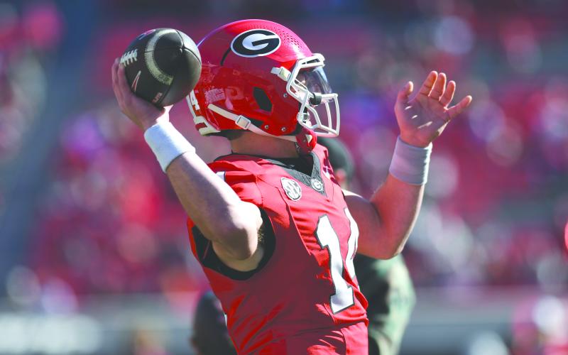 Wade Cheek/The Clayton Tribune. Gunner Stockton led a three-and-a-half minute, eight-play, 65-yard drive in the fourth quarter of Georgia’s 59-21 win over UMass on Saturday, Nov. 23. Stockton completed three of four passes for 45 yards.  BELOW: Starting senior quarterback Carson Beck stiff-arms a UMass defender en route to short scramble in the first half of Georgia’s 59-21 win over the Minutemen.
