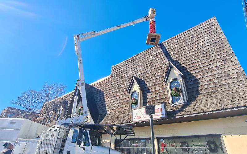 Megan Horn/The Clayton Tribune. City of Clayton workers spend hours on Monday installing the iconic candle atop Reeves at the intersection of Main Street and East Savannah Street. Santa Claus will light the candle on Saturday, Dec. 7, at the end of the parade.