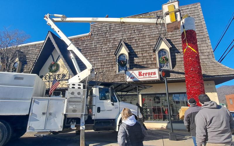 Megan Horn/The Clayton Tribune. City of Clayton workers spend hours on Monday installing the iconic candle atop Reeves at the intersection of Main Street and East Savannah Street. Santa Claus will light the candle on Saturday, Dec. 7, at the end of the parade.