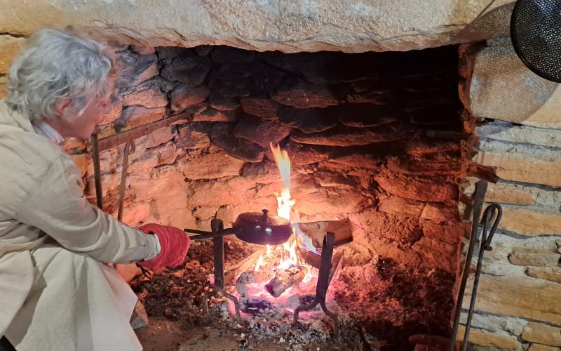 Megan Horn/The Clayton Tribune. Foxfire demonstrator Aleta Yates shows visitors to the Foxfire Village how to make popcorn over an open fire at the Savannah Cabin during “A Foxfire Christmas” Dec. 7. The Savannah Cabin is the oldest on the property.