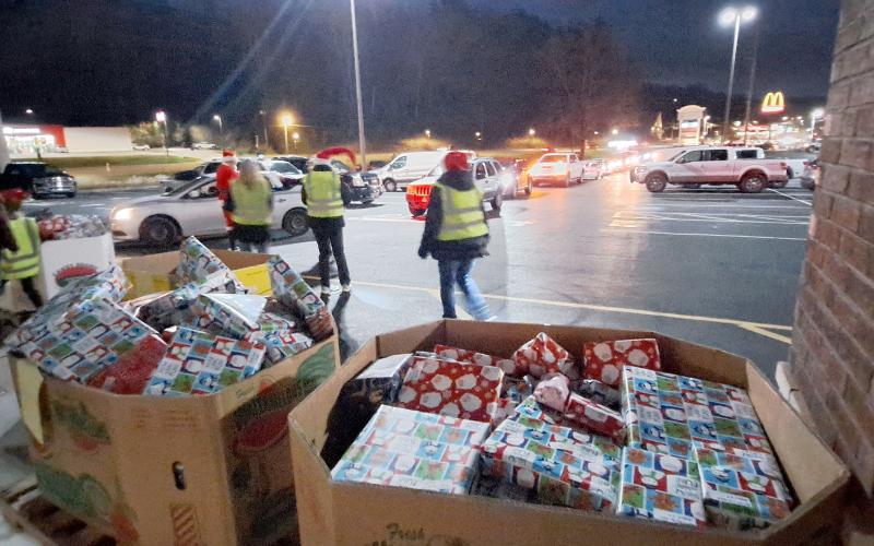 Megan Horn/The Clayton Tribune. Volunteers at the Food Bank Toy Drive prepare to hand out gifts as a row of vehicles wraps around the Food Bank parking area on Monday.