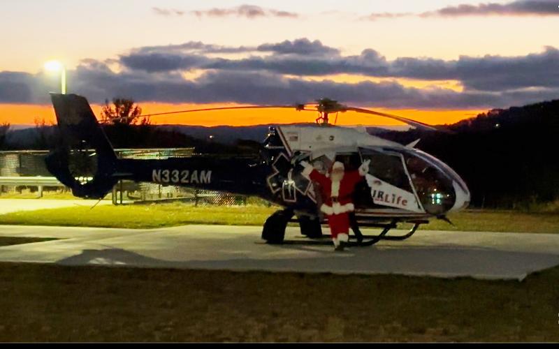Photo courtesy Mountain Lakes Medical Center. With the sunset in the background, Santa exits an AirLife helicopter at Mountain Lakes Medical Center to visit local youth on Dec. 19.
