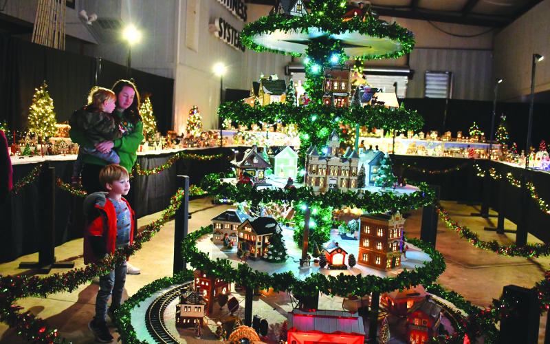 File photo/Megan Horn. The Stille family of Spencer, Jennifer and Sutton gaze at the miniature village that includes a train at last year's Village of Lights benefitting Fight Abuse In The Home (F.A.I.T.H.).