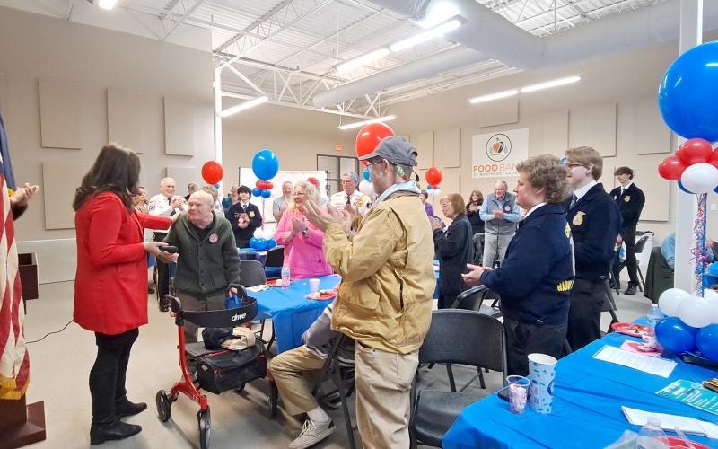 Megan Horn/The Clayton Tribune. Attendees at the February Vet-to-vet Cafe give 101-year-old WWII U.S. Navy Veteran Lt. J.G. Dr. Eldred Causey a standing ovation and sing “Happy Birthday.” Pictured left beside Causey is Carolyn Culpepper with Family Hospice and right is Causey’s daughter Kathy Causey.