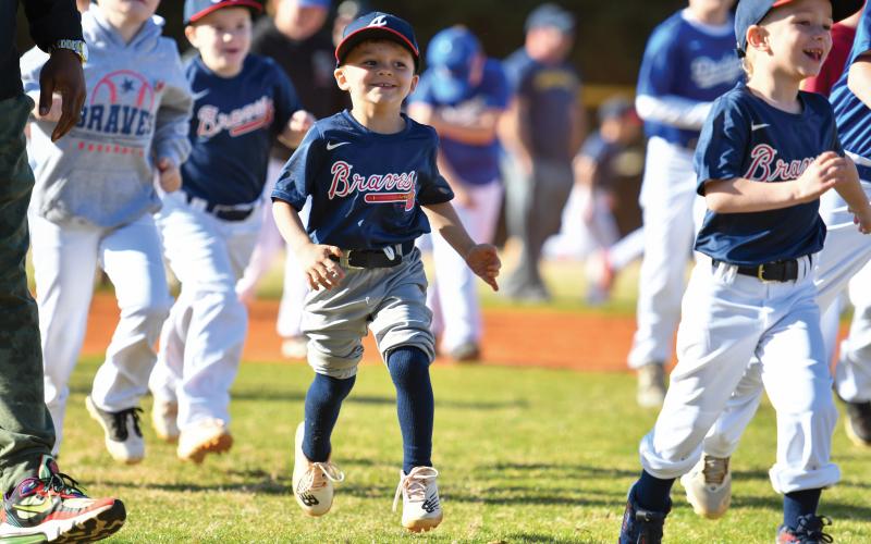 Wade Cheek/The Clayton Tribune. Davis Leverette joins the rest of RCLL in running to home plate for a performance by former MLB player and musical artist CJ Beatty. RCLL held its opening day ceremony to kick off the new season.