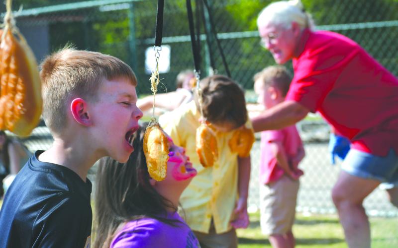 Enoch Autry/The Clayton Tribune.  As a doughnut swings back and forth on a string, 7-year-old Blaine Ancelet prepares to take a chomp out of the food.