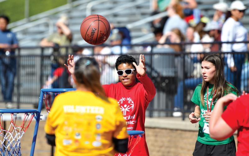 Wade Cheek/The Clayton Tribune. With his buddy Abby Thurmond watching, Nathan Dugas sinks a basket in the basketball event at the Rabun County Special Olympics on Thursday, April 17.  The local Special Olympics returns after a six-year hiatus.